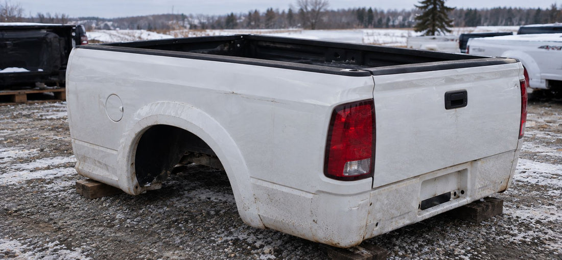 Used truck box with minor dents displayed outdoors in a gravel lot during winter conditions, representing rust-free replacement truck parts for Canadian winters.